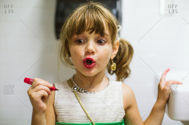 Girl putting on lip liner in bathroom