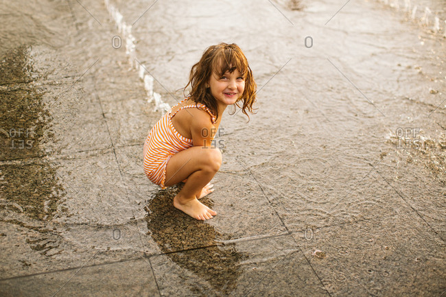Girl squatting in fountain in park