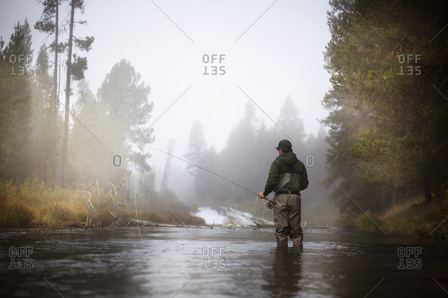 A man stands in a river fishing
