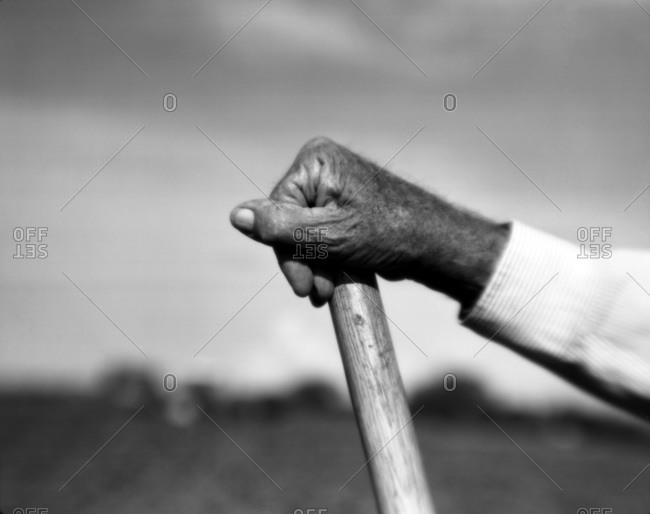 Detail of an older African American man\'s hand holding on to the tip of a shovel
