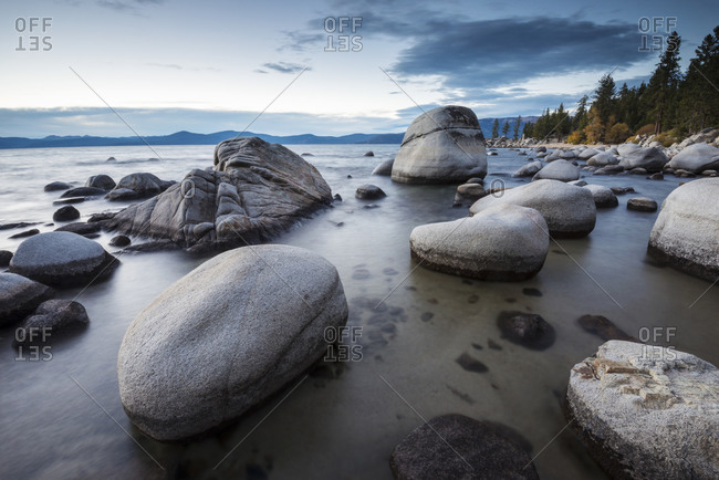 Dusk sets in over the calm waters and granite boulders, east shore of Lake Tahoe, Nevada