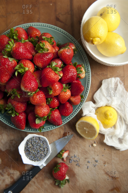 Overhead shot of plate of strawberries with lemons and lavender on kitchen counter