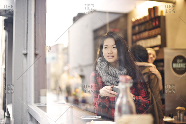 Young woman staring out the window of a cafe