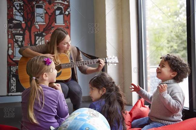 Teacher playing guitar for students