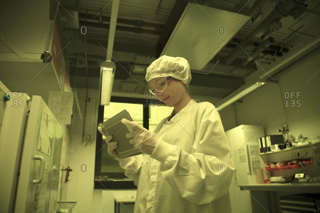 Woman with digital tablet working in a clean room unit