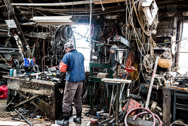 Man surrounded by wires and cables in a messy workshop