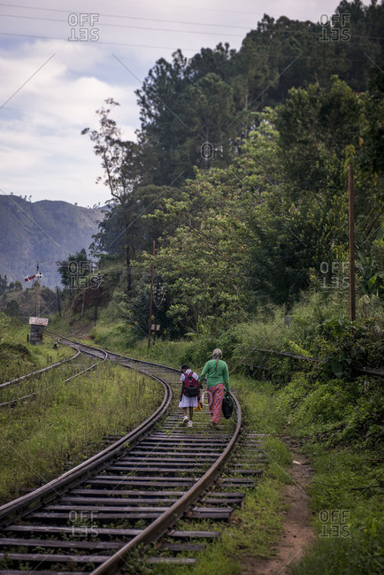 Back view of woman and child walking on train tracks