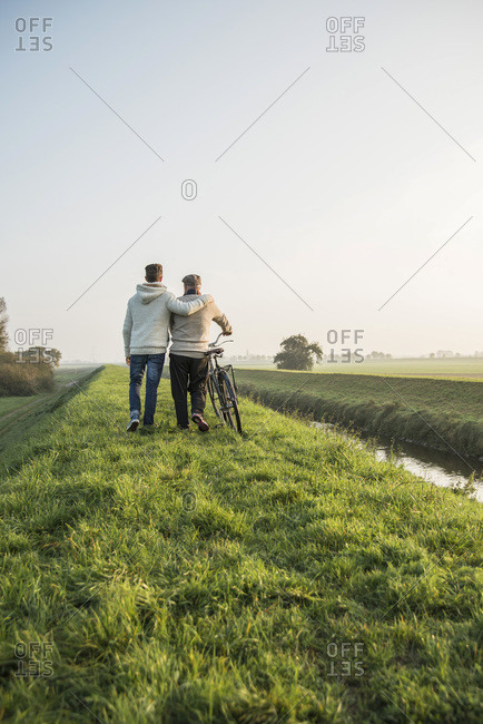 Senior man and grandson in rural landscape with bicycle