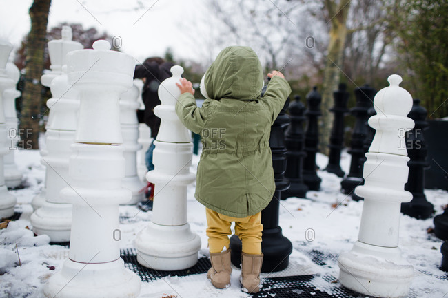 A little girl walks across a giant chess board