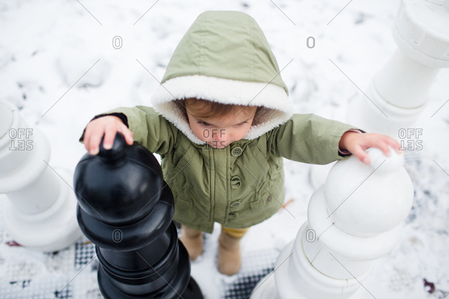 A little girl walks across a giant chess board