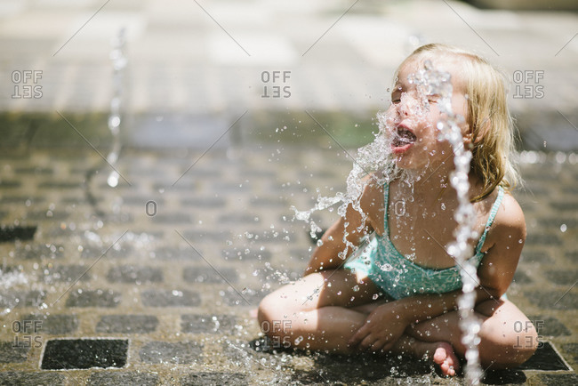 Young girl drinking from a fountain at the Klyde Warren park in Dallas, Texas, USA