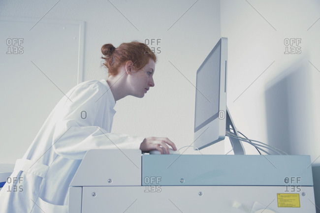 Young female natural scientist working at computer in biochemistry laboratory