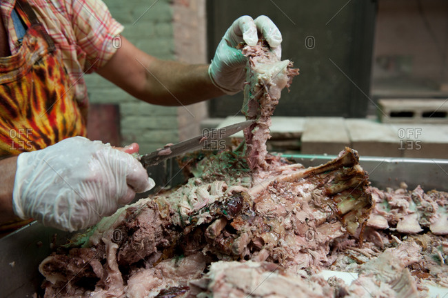 Chef cutting the meat off a roasted pig