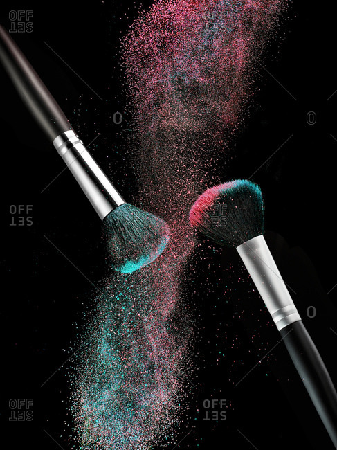 Color make-up powder and two beauty brushes in front of black background
