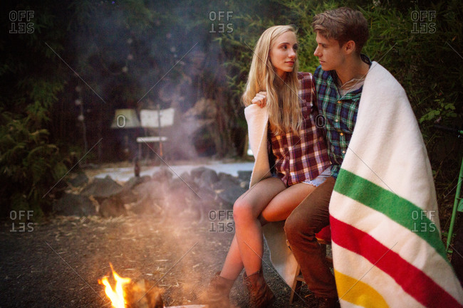 Young couple under blanket by fire