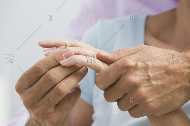Senior couple man putting diamond ring on woman\'s finger detail of hands