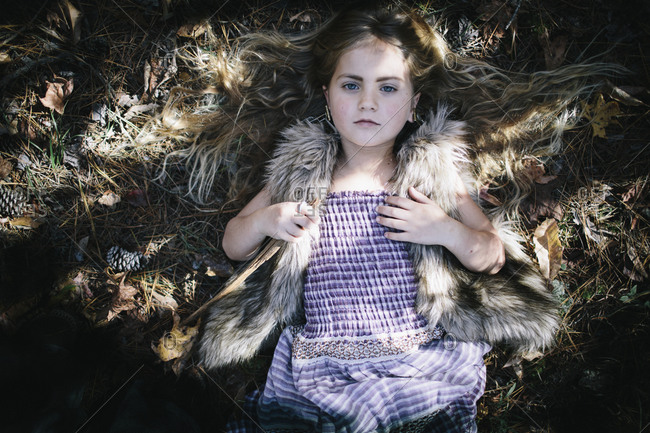 A girl lays outside in pine needles