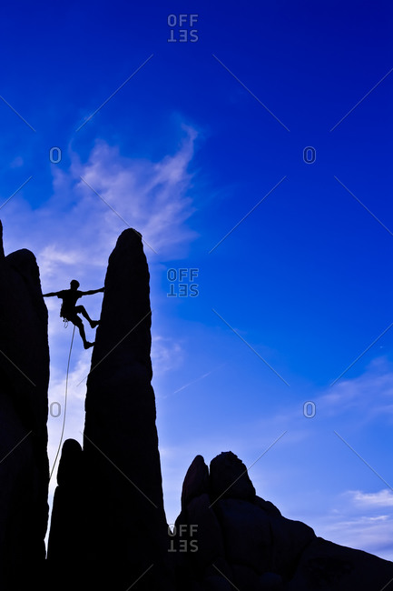 Silhouette of man climbing up a rock formation
