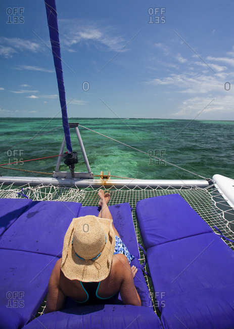 A woman lounges on the front of a catamaran enjoying a cruise in the Caribbean