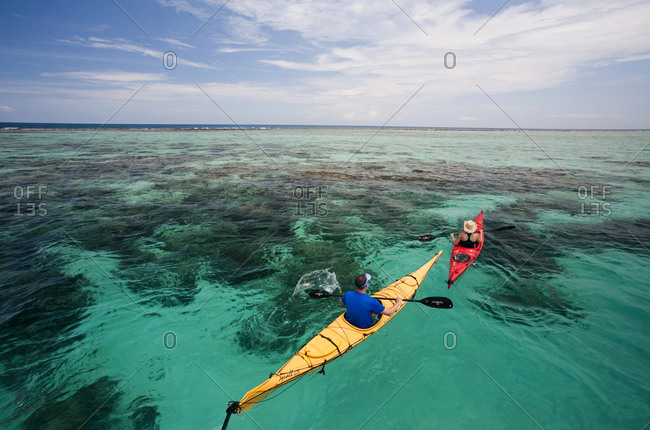 A couple sea kayak in the clear waters off the coast of Belize