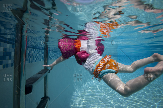 Toddler reaches for pool ladder underwater