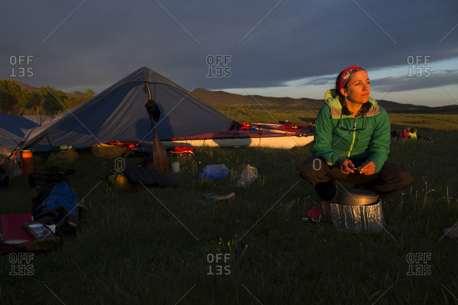 A woman tends to the hot water on the camp stove beside the campsite on the river bank of the Onon river in northern Mongolia.