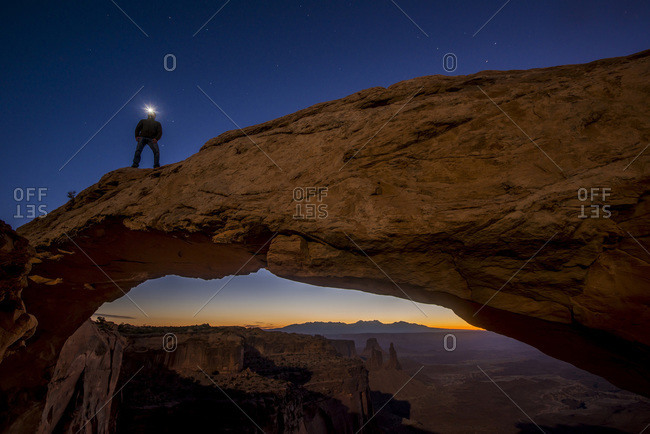 Man with a headlamp standing on top of Mesa Arch at Canyonlands National Park, Utah, USA