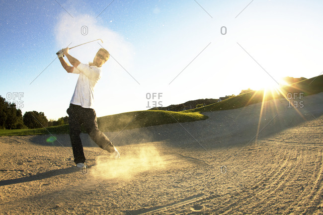 A man hitting golf ball out of sand trap