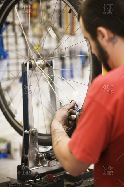A bicycle repairman tuning wheel spokes