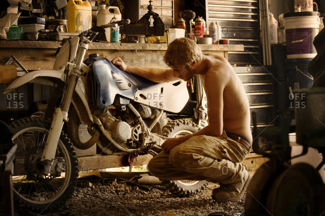 A young man in his garage with his motorcycle