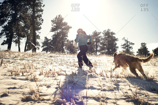 Dog chasing woman uphill in snow