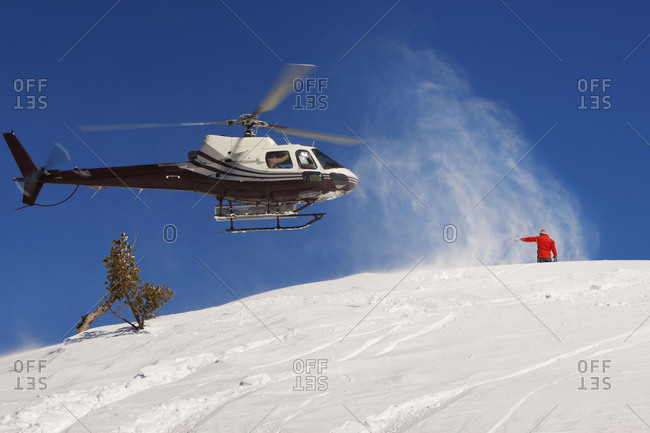 Man directing helicopter on snow-covered mountain