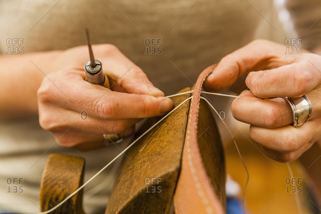 Woman sewing elastic fabric rubber band using lacing pony and awl