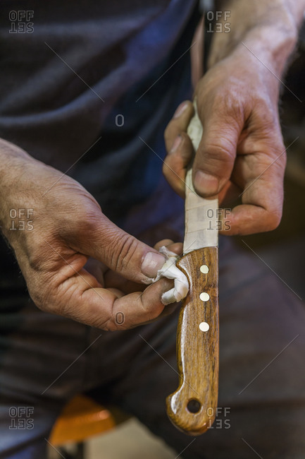 Knife maker rubbing linseed oil on knife handle
