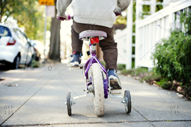 A child rides a bike with training wheels
