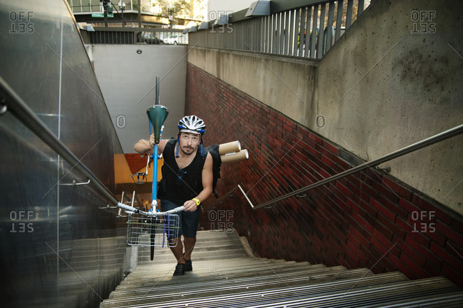 A man carries his bike up subway stairs