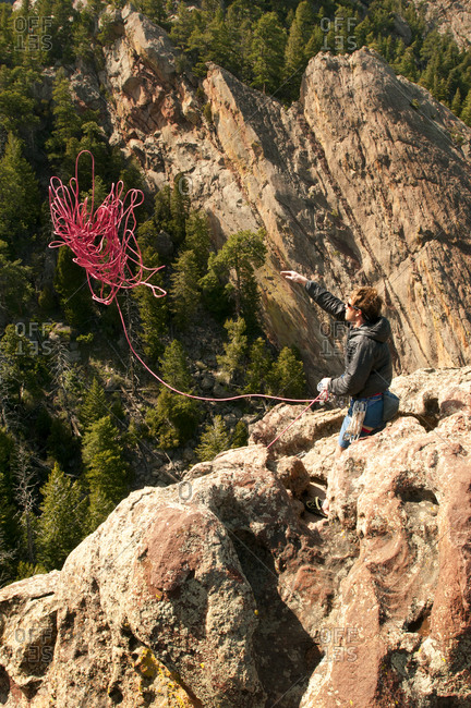 Rock climber throwing rope off cliff