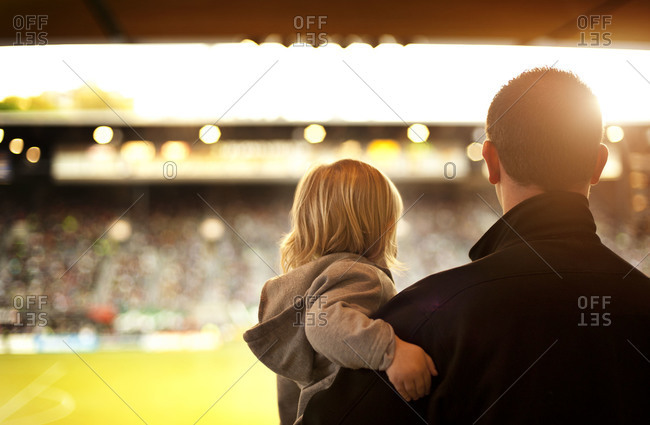 A man holds his little girl at a soccer game