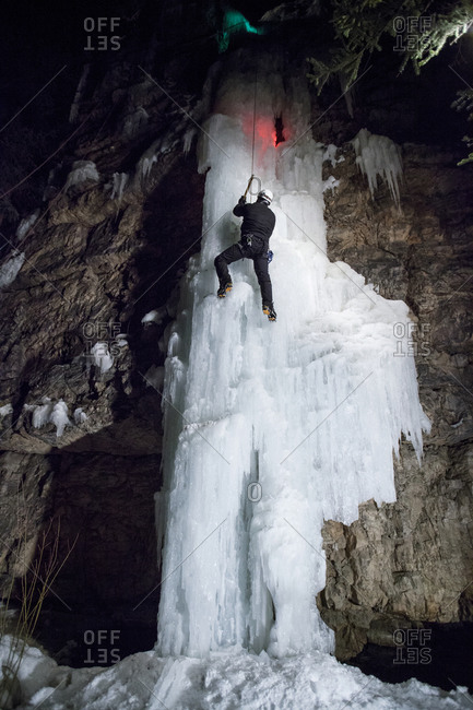 A man ice climbing at night