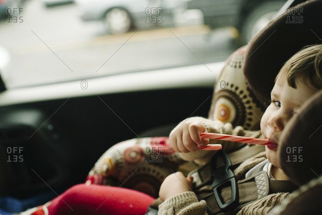 Young child eating candy can in car seat