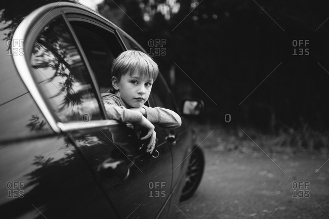 Boy looking out car window in woods