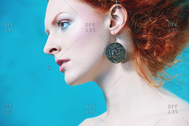 Close up of a red haired lady with a round copper earring