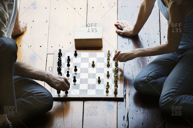Couple playing chess together on a wood floor