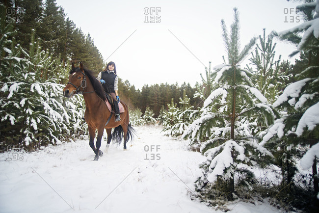 Young Woman Horseback Riding Through Snow