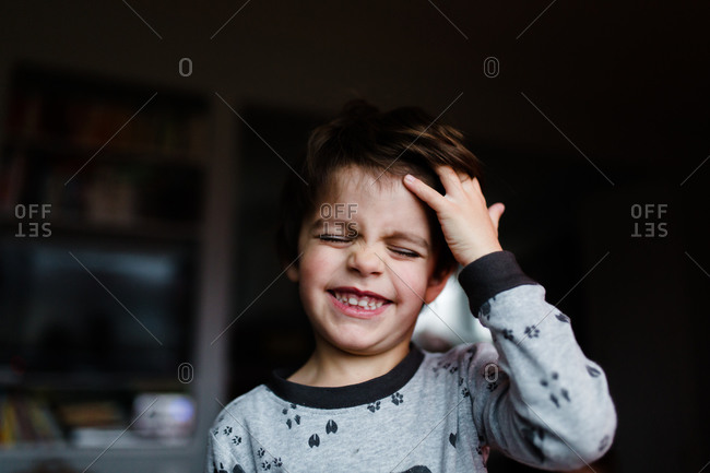A little boy scratches his head