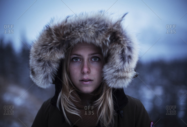 A pretty young blond woman keeps warm in her winter parka in Banff National Park, Alberta