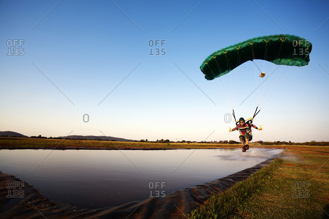 Parachutist landing on shallow pond