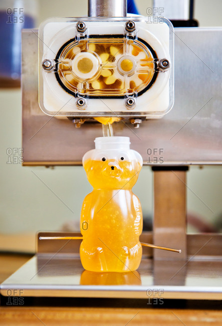 Machine dispensing honey into plastic honey bear