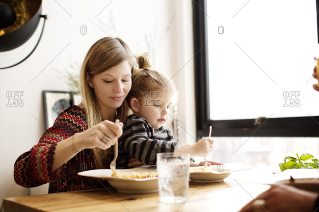 Mother and daughter eating pasta