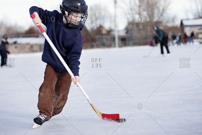 A boy plays ice hockey outside